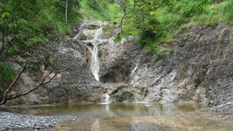 A waterfall cascades into a pool in the mountains Video stock 212745405