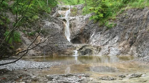 A waterfall cascades into a pool in the mountains Stock-Footage 212745783