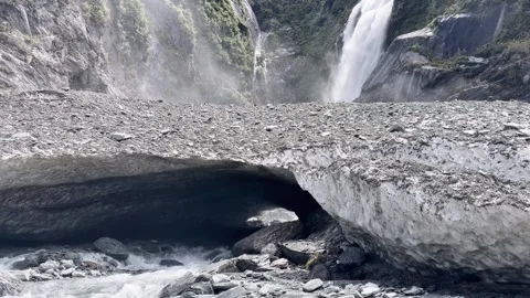 Waterfall cascading above a snow cave in Mount Aspiring National Park. Stock Footage 343839685