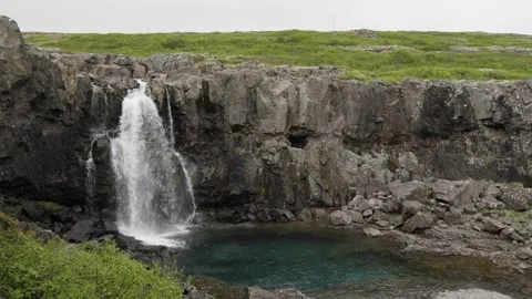 Waterfall Cascading Into Clear Pool in Rugged Icelandic Landscape 4K Nature Stock Footage 339737810