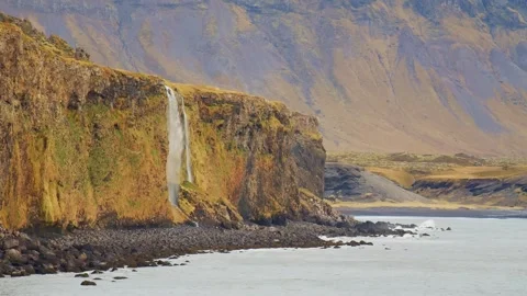 Waterfall Cascading from a Cliff into the Ocean on the Coast of Iceland Stock Footage 320202482