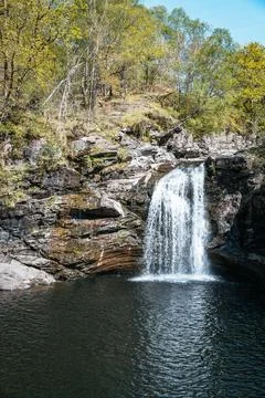 Waterfall cascading into a deep pool amidst lush forest in the Scottish Stock Photos