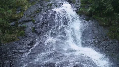 Waterfall cascading down dark wet rocky mountain cliff in forest environment Stock Footage 342326208