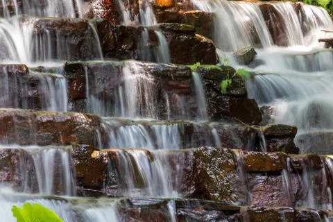 A waterfall cascading down from layers of rock 스톡 사진