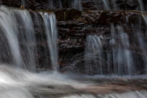 A waterfall cascading down from layers of rock Stock Photos