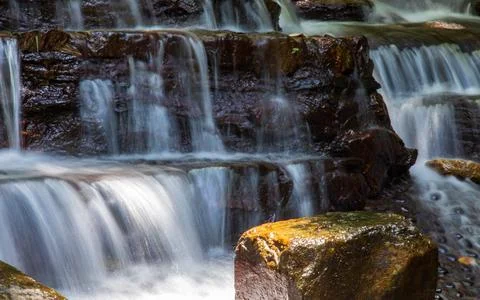 A waterfall cascading down from layers of rock Stock Photos