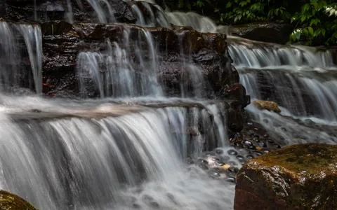 A waterfall cascading down from layers of rock Stock Photos