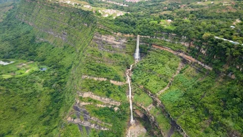 Waterfall cascading down a lush green hillside Stock Footage 329950032