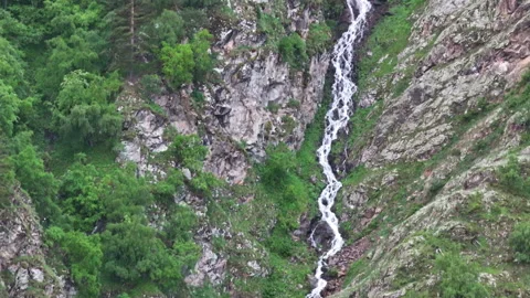 Waterfall cascading down mountainside in green forest Stock Footage 289684824