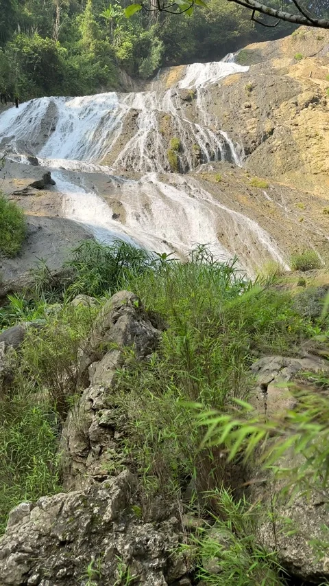 Waterfall Cascading Down Rocks, Lush Jungle Scenery, Vertical Reveal Shot Stock Footage 325645831
