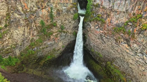 Waterfall cascading down rocky canyon cliff drone shot Stock Footage 344137783