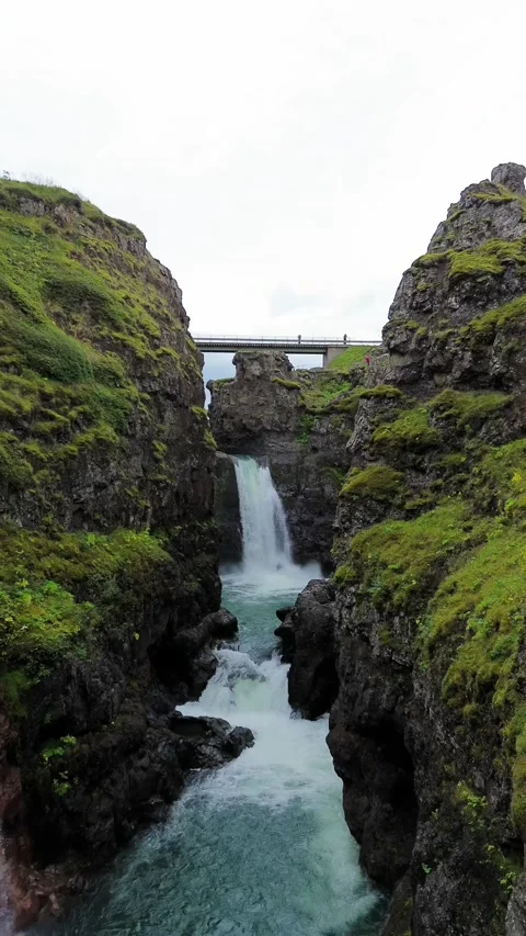 Waterfall cascading down rocky cliff surrounded by moss in Iceland Stock Footage 318660765