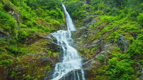 Waterfall cascading down rocky mountain cliff in forest Stock Footage 344137679