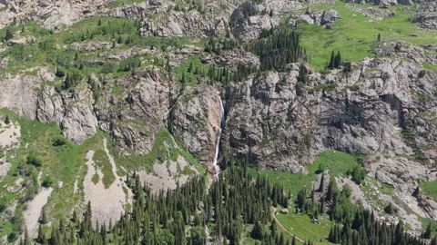 Waterfall cascading down rocky mountainside in lush green valley Stock-Footage 312435963