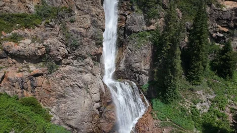 Waterfall cascading down rocky mountainside in summer Stock Footage 312436790