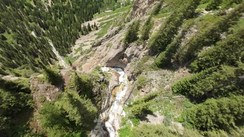 Waterfall cascading down rocky mountainside in green valley Video stock 312540104