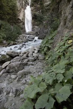 Waterfall cascading down rocky mountainside with river Stock Photos