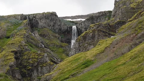Waterfall Cascading Down Steep Rocky Cliff in Iceland Nature Footage Stock Footage 339753522