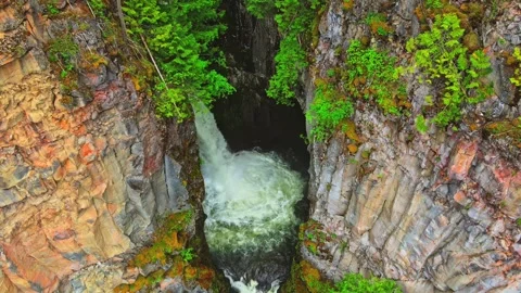 Waterfall cascading into narrow rocky gorge aerial shot Video stock 344137785