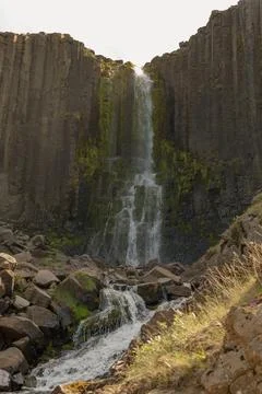 Waterfall Cascading Over Basalt Columns in Iceland's Rugged Landscape Stock Photos