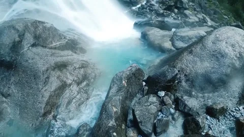 Waterfall cascading over dark rocks into a turquoise pool Stock Footage 302309109
