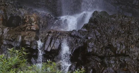 Waterfall cascading over dark wet rocks in tropical forest Stock Footage 332387356