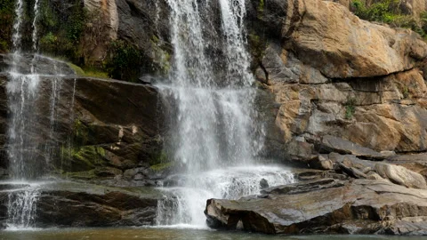 Waterfall cascading over rocky terrain in a serene landscape Stock Footage 301559779