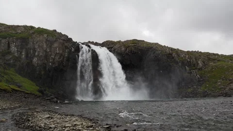 Waterfall Cascading Over Rugged Rocky Cliff in Iceland Nature Footage Stock Footage 339753453