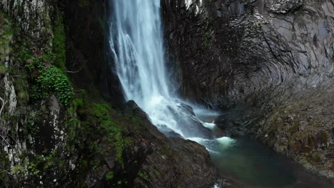 Waterfall Cascading Through Narrow Rocky Canyon with Moss-Covered Walls Stock Footage 345954906