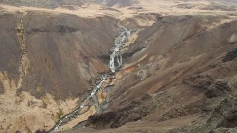 Waterfall cascading through a steep rocky canyon under soft daylight in the N Stock Footage 336763089
