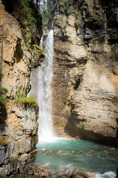 Waterfall cascading into turquoise pool, surrounded by rocky cliffs Stock Photos