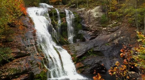 Waterfall - Cascading waterfall bordered by autumn leaves MS Stock Footage 57649578