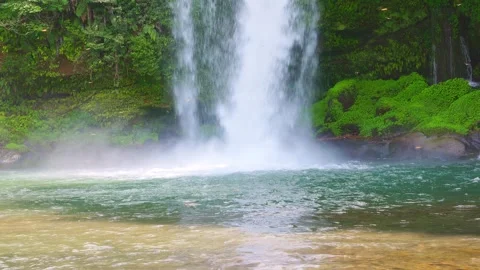 Waterfall crashing into clear basin with spray and flowing ripples 動画素材 341806349