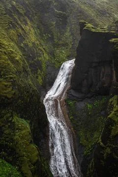 Waterfall cuts through mossy basalt canyon in Iceland volcanic highlands Stock Photos
