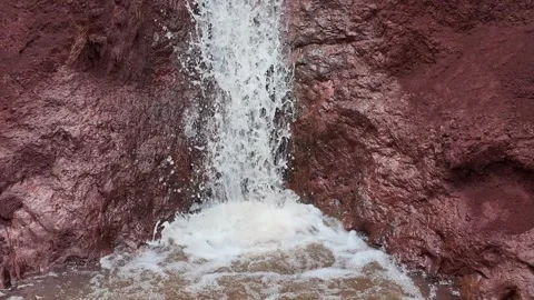 Waterfall dropping down a rust-red cliff face into a pool on Kauai Stockbeeldmateriaal 347826227