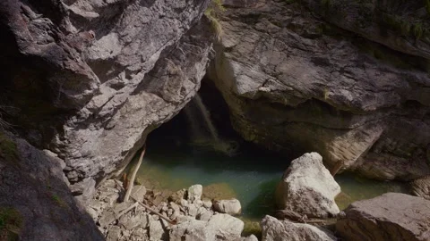 Waterfall falling from a cave ceiling into a magical turquoise pool at Stock Footage 335275938