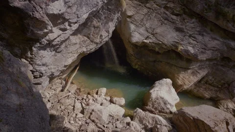 Waterfall falling from a cave ceiling into a magical turquoise pool at Stock Footage 335275952