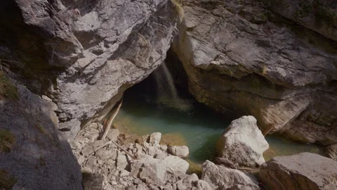 Waterfall falling from a cave ceiling into a magical turquoise pool at Stock Footage 335964718