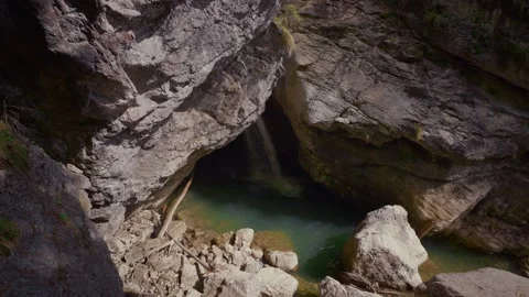 Waterfall falling from a cave ceiling into a magical turquoise pool at Stock Footage 336288072