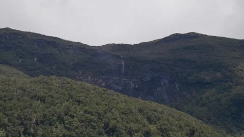 Waterfall falling off cliff high above water Stock Footage 328575129
