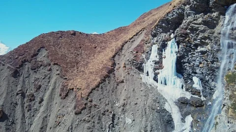 Waterfall falling from iced cliff, snow peak at horizon, river gorge, panorama Stock Footage 126724057