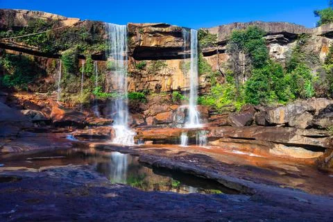 Waterfall falling from mountain top with reflection and blue sky at morning f Foto stock