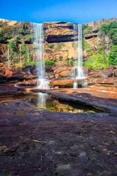 Waterfall falling from mountain top with reflection and blue sky at morning f Foto stock