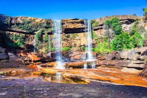 Waterfall falling from mountain top with reflection and blue sky at morning f Stock Photos