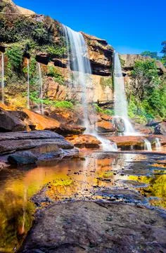 Waterfall falling from mountain top with reflection and blue sky at morning f 写真素材