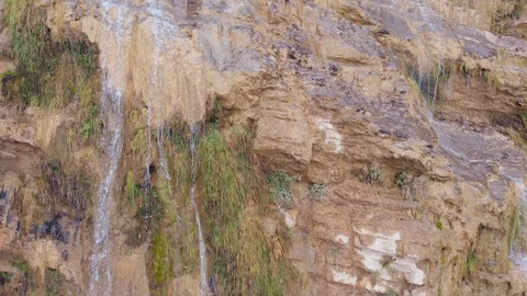 Waterfall falling from a rocky mountain, aerial shot, camera moves from top to Stock-Footage 104106926