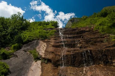 Waterfall falling from slope rocks Stock Photos