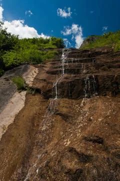 Waterfall falling from slope rocks Stock Photos
