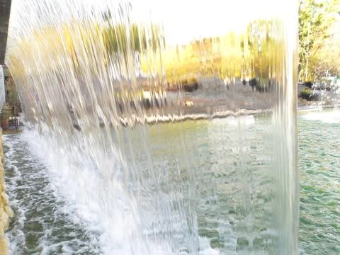 Waterfall Flow Over Stone Wall in City Park Stock Photos