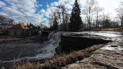 Waterfall flowing beside a historic mill under a blue sky, static shot Stock Footage 337555166